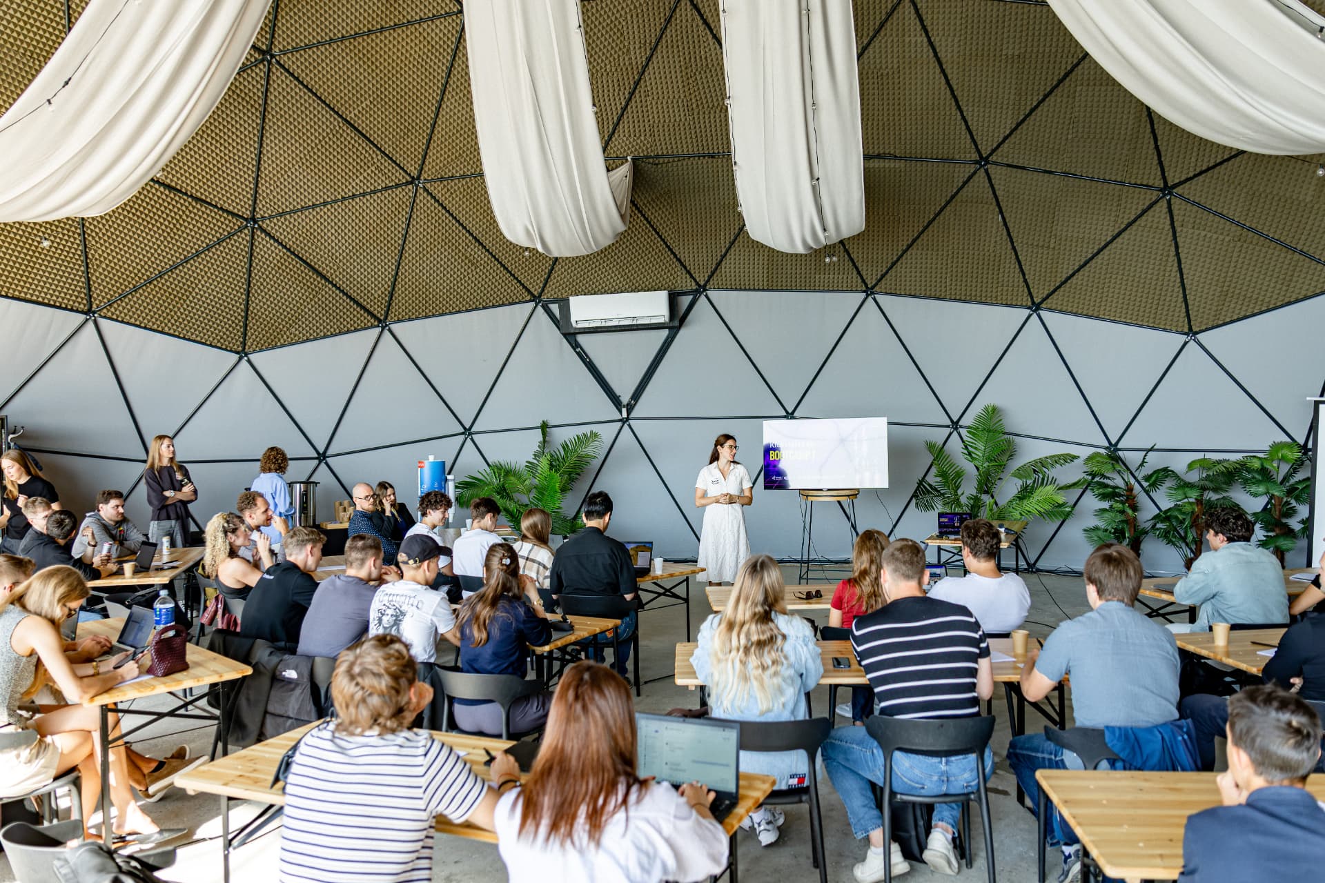Participants listening to a speaker during a startup bootcamp in a geodesic dome